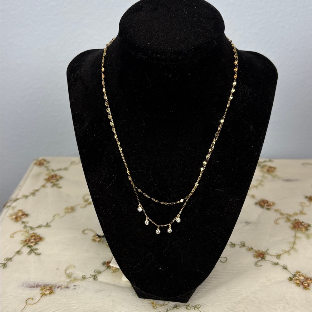 Bezel- set CZ charms sparkle and shine from a layered chain.